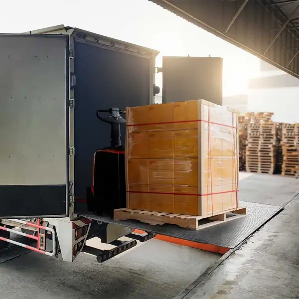 Palletised cargo being loaded into a box truck at a loading dock.