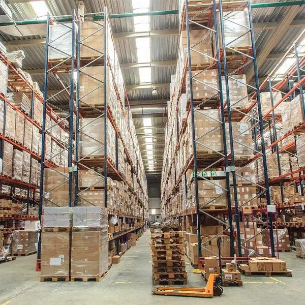 Warehouse aisle of racking stacked with palletised goods, a pallet truck in the foreground.
